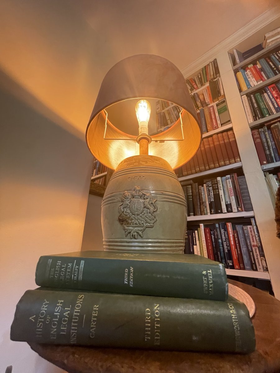Vintage reading lamp beside old English legal-history books in a private law library.